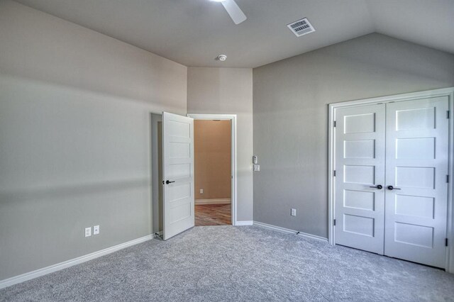 unfurnished bedroom with ceiling fan, a closet, carpet floors, and vaulted ceiling