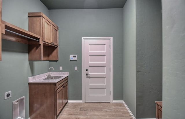 laundry area with cabinets, sink, hookup for an electric dryer, and light wood-type flooring