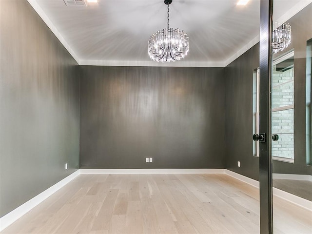 spare room with ornamental molding, light hardwood / wood-style floors, and a notable chandelier