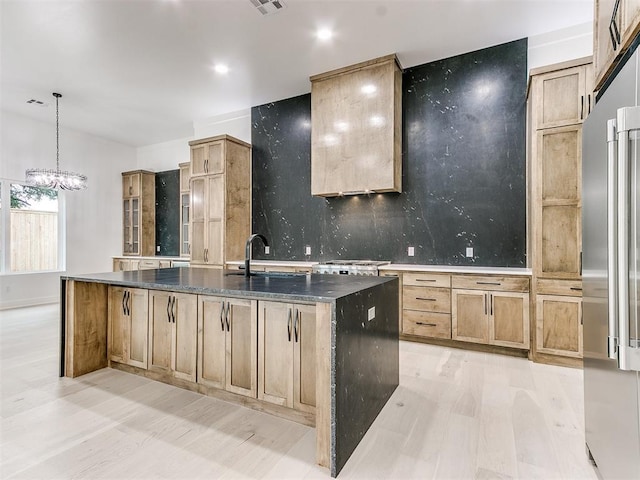 kitchen with pendant lighting, an island with sink, an inviting chandelier, backsplash, and sink