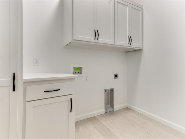 washroom featuring electric dryer hookup, hookup for a washing machine, cabinets, and light hardwood / wood-style flooring