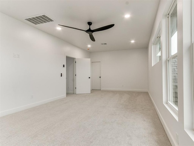 carpeted spare room with ceiling fan and plenty of natural light