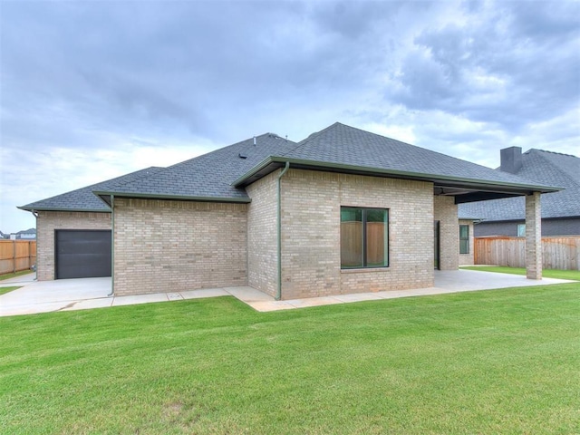 back of property with a lawn, a garage, and a patio