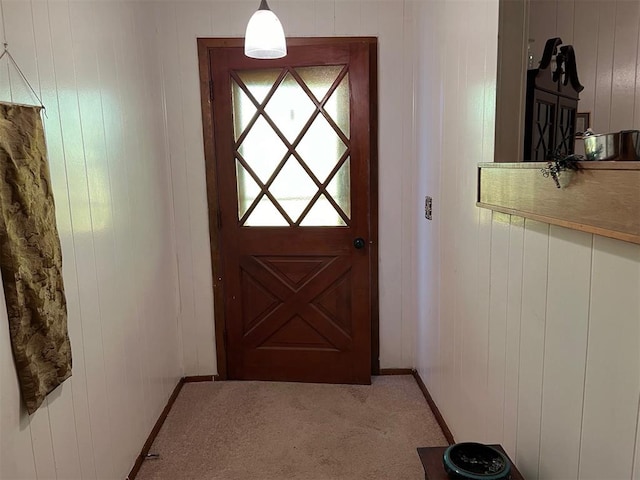 doorway with light carpet and wood walls