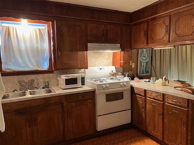 kitchen with decorative backsplash, sink, white appliances, and dark tile patterned floors