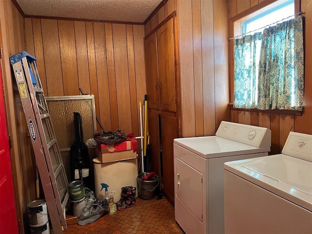 clothes washing area with washer and dryer, wooden walls, and a textured ceiling