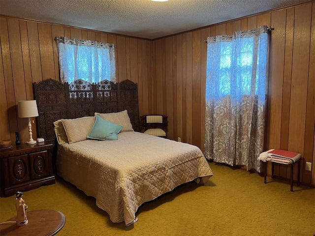 bedroom with light colored carpet, a textured ceiling, and wood walls