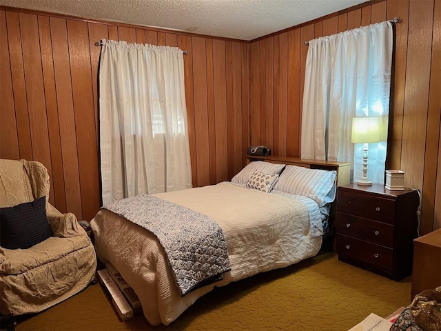 carpeted bedroom with a textured ceiling and wood walls