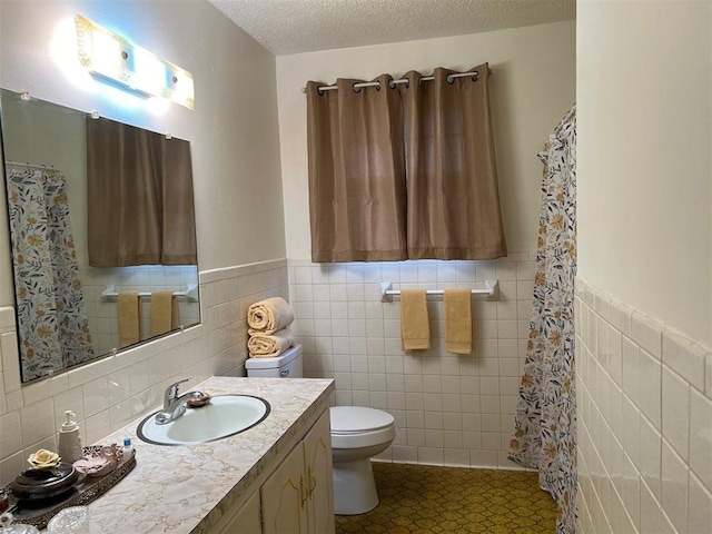 bathroom with toilet, tile walls, tile patterned floors, a textured ceiling, and vanity