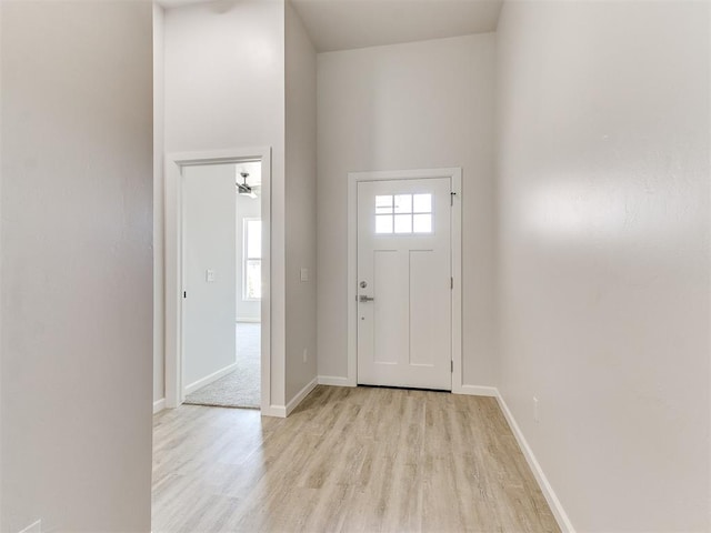 foyer entrance featuring a high ceiling, ceiling fan, and light hardwood / wood-style flooring