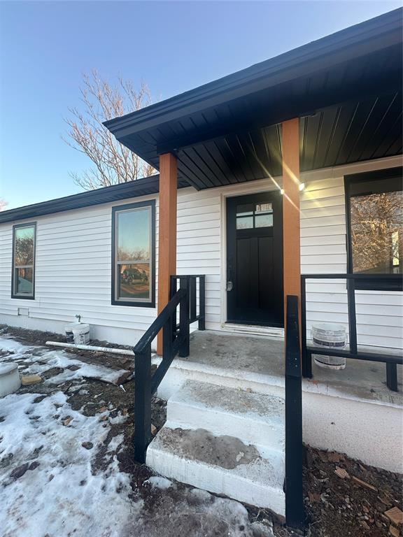 snow covered property entrance featuring covered porch