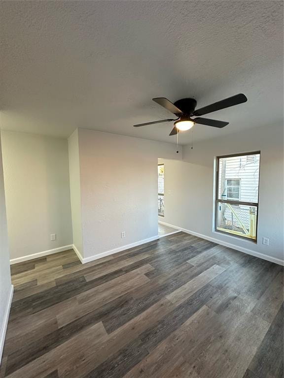 empty room with ceiling fan, dark hardwood / wood-style flooring, and a textured ceiling