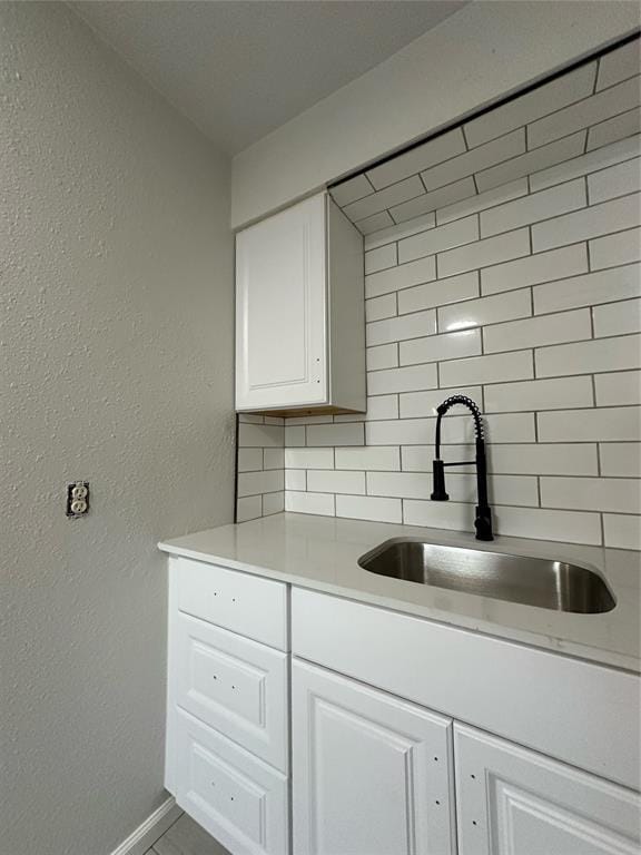 interior space with sink, white cabinets, tile patterned floors, and backsplash