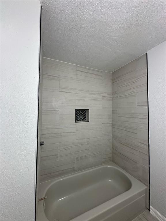 bathroom with a textured ceiling and shower / tub combination