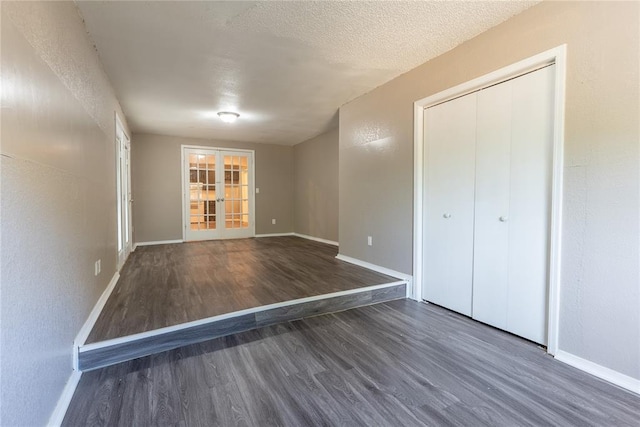 interior space featuring a closet, french doors, dark wood-type flooring, and a textured ceiling