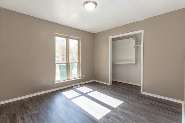 unfurnished bedroom with a closet and dark wood-type flooring