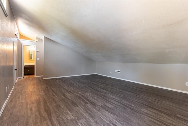 bonus room featuring dark wood-type flooring and vaulted ceiling