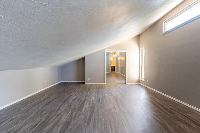 additional living space with dark hardwood / wood-style floors, a textured ceiling, and lofted ceiling