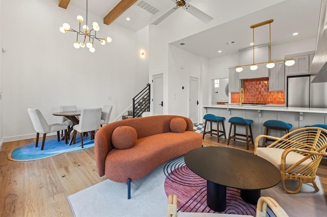 living room featuring ceiling fan with notable chandelier, light hardwood / wood-style floors, and beam ceiling