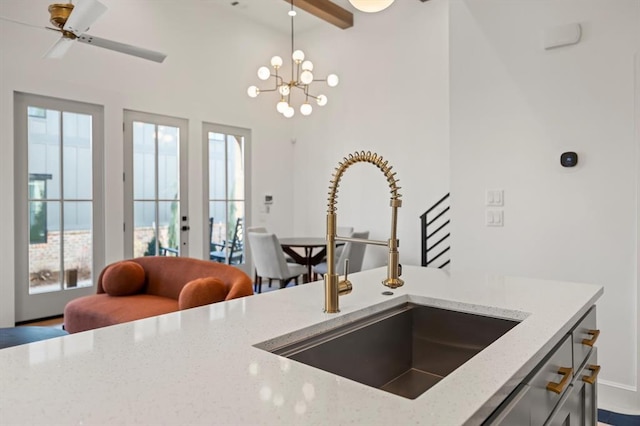 kitchen with light stone countertops, a healthy amount of sunlight, pendant lighting, and sink