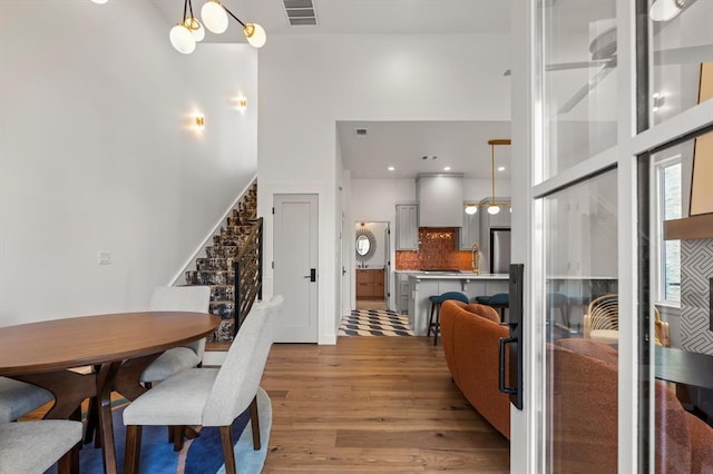 dining area with a high ceiling, light wood-type flooring, sink, and a chandelier