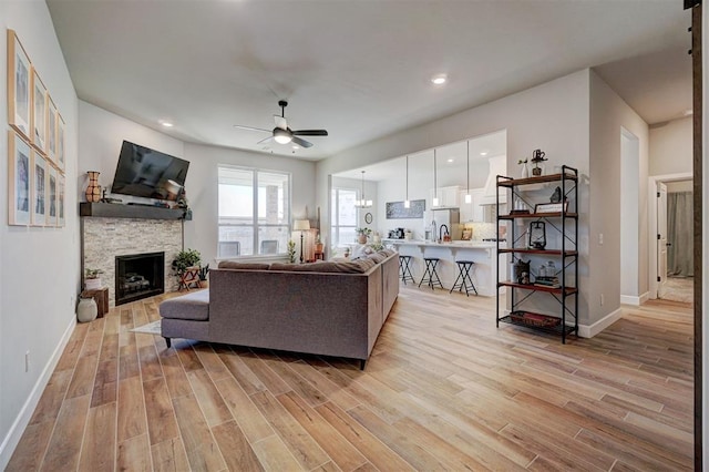 living room with ceiling fan and a stone fireplace