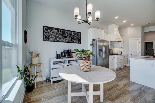 kitchen with stainless steel appliances, custom range hood, sink, and white cabinets