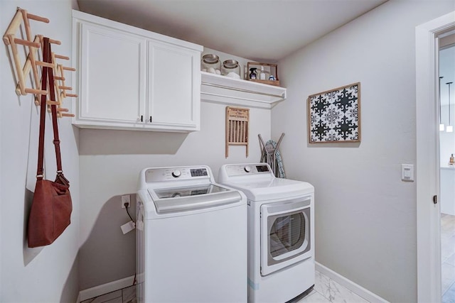 clothes washing area featuring washing machine and clothes dryer and cabinets