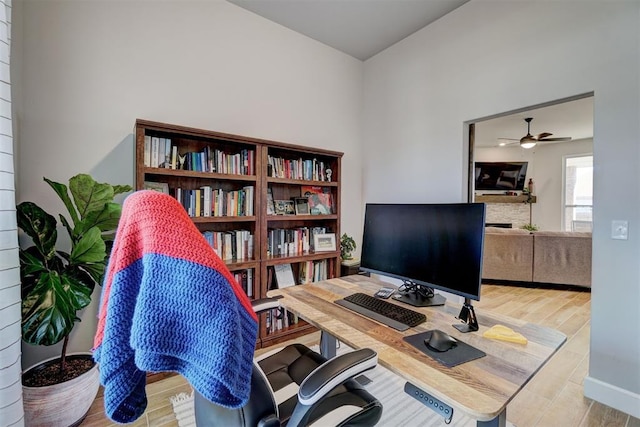 office area featuring ceiling fan and a stone fireplace