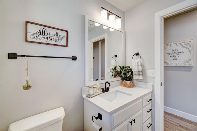 bathroom featuring toilet, vanity, and hardwood / wood-style floors