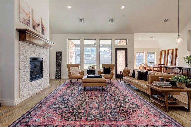 living room featuring a fireplace, high vaulted ceiling, and light wood-type flooring