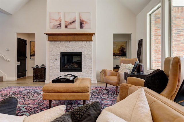 living room with a stone fireplace, vaulted ceiling, and light hardwood / wood-style floors