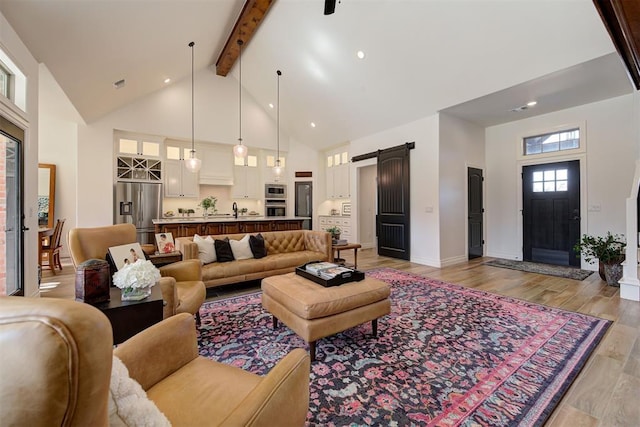 living room with a barn door, light wood-type flooring, high vaulted ceiling, and beam ceiling