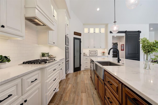 kitchen with pendant lighting, a barn door, white cabinets, and appliances with stainless steel finishes