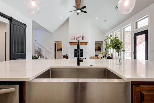 kitchen with light stone counters, decorative light fixtures, high vaulted ceiling, and a barn door