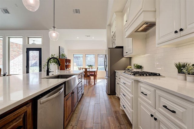 kitchen featuring dark wood-type flooring, appliances with stainless steel finishes, hanging light fixtures, backsplash, and white cabinets