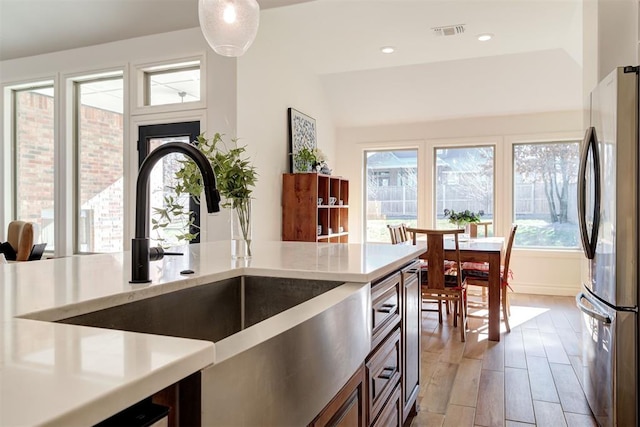 kitchen featuring a healthy amount of sunlight, stainless steel fridge, light hardwood / wood-style floors, and sink