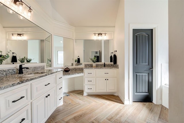 bathroom featuring vanity, parquet flooring, and vaulted ceiling