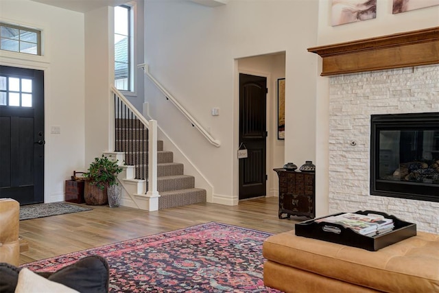 foyer with a towering ceiling, a fireplace, and light wood-type flooring