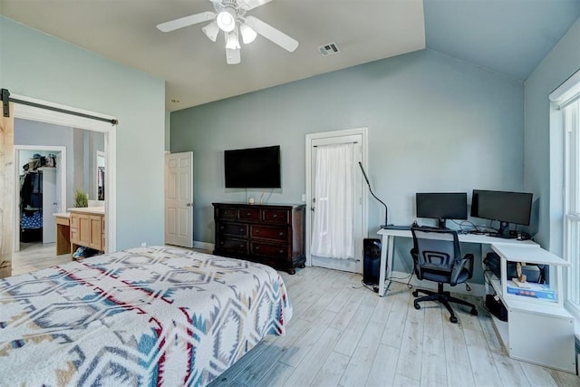 bedroom featuring lofted ceiling, ceiling fan, light hardwood / wood-style floors, and a barn door