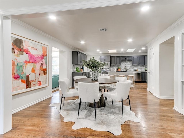 dining space with light hardwood / wood-style flooring and ornamental molding