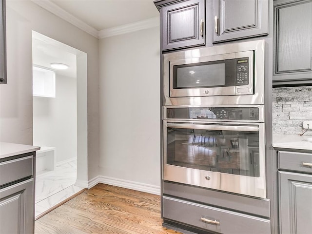 kitchen featuring light hardwood / wood-style floors, crown molding, gray cabinetry, and stainless steel appliances