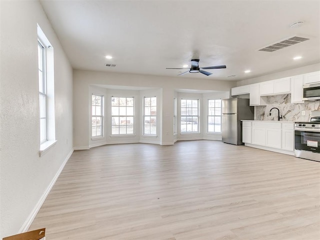 unfurnished living room featuring ceiling fan, sink, and light hardwood / wood-style flooring