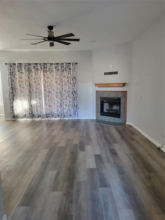 unfurnished living room featuring dark wood-type flooring, ceiling fan, and a fireplace