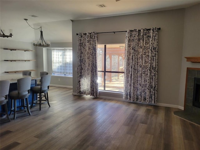 dining room with dark hardwood / wood-style flooring, a tile fireplace, and an inviting chandelier