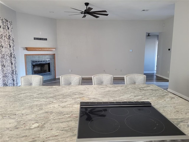 kitchen featuring ceiling fan, cooktop, and a fireplace