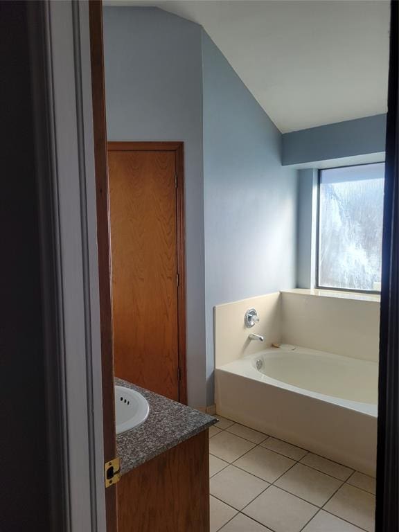 bathroom featuring vanity, tile patterned flooring, and a washtub