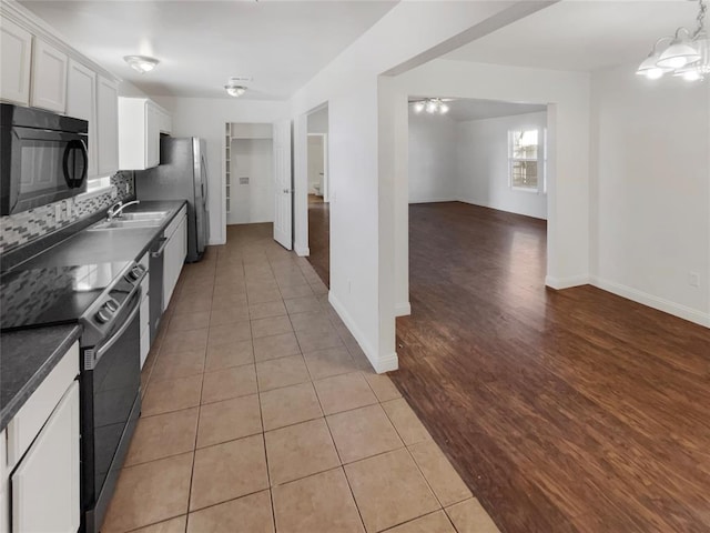 kitchen featuring white cabinets, black appliances, decorative backsplash, sink, and light tile patterned flooring