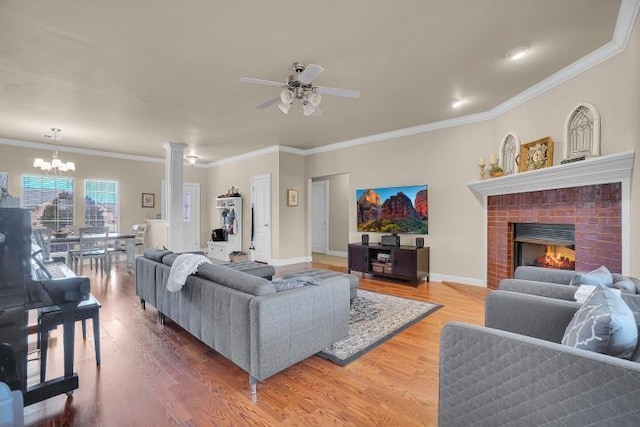 living room featuring crown molding, a brick fireplace, hardwood / wood-style floors, and ceiling fan with notable chandelier