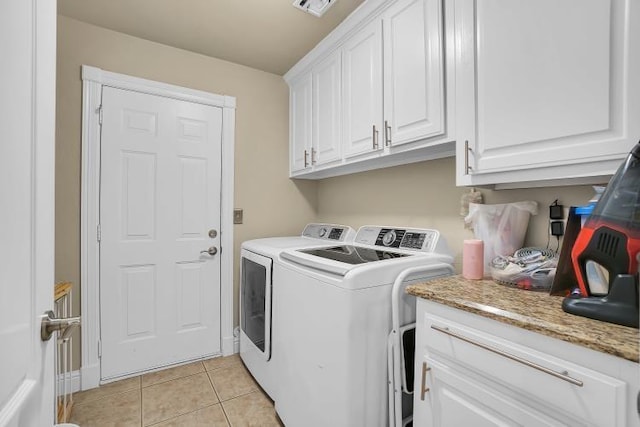 clothes washing area with cabinets, light tile patterned flooring, and washer and dryer